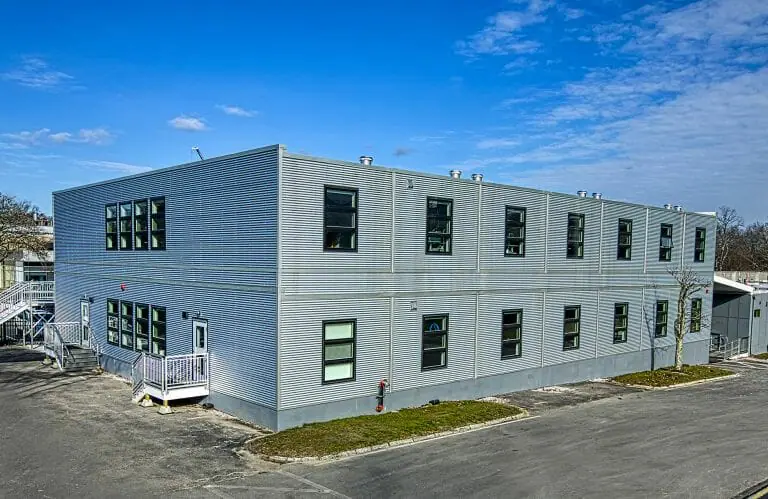 Bâtiment modulaire de deux étages avec bardage en tôle ondulée galvalume, fenêtres classées Energy Star et système CVC avancé pour la ventilation de l'air frais, conçu pour un client biotechnologique du Massachusetts afin de maximiser l'occupation et la durabilité.