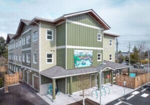 Bâtiment modulaire permanent de trois étages avec revêtement extérieur vert et grande fresque murale.