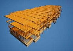 Grande structure industrielle en acier jaune vue d'en bas, sur fond de vaste ciel bleu.