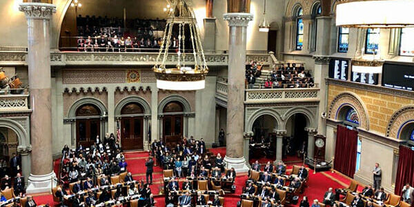 Des fonctionnaires se réunissent dans une chambre législative pour discuter de la promotion de la construction modulaire.
